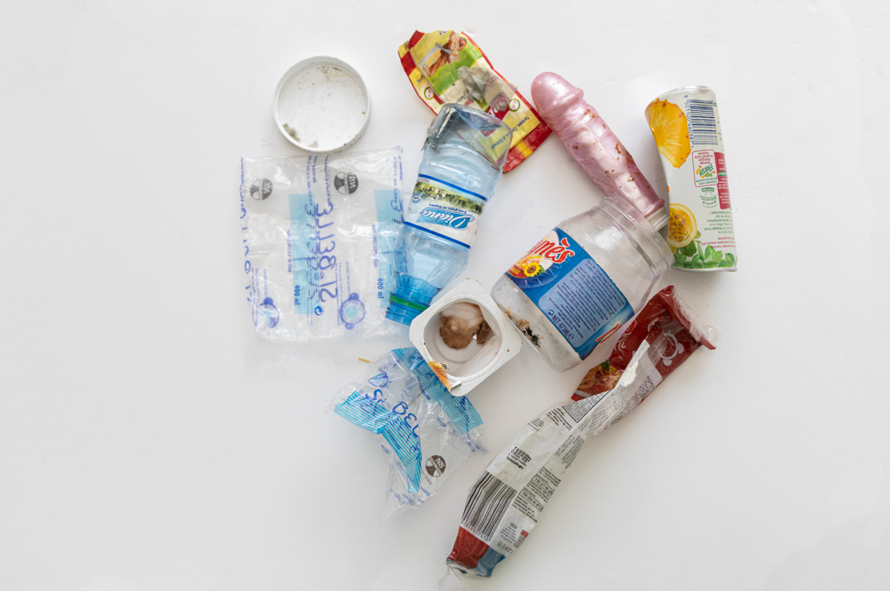 Photographie de déchets plastiques et non-organiques prise d'un point de vue en plongée sur fond blanc.